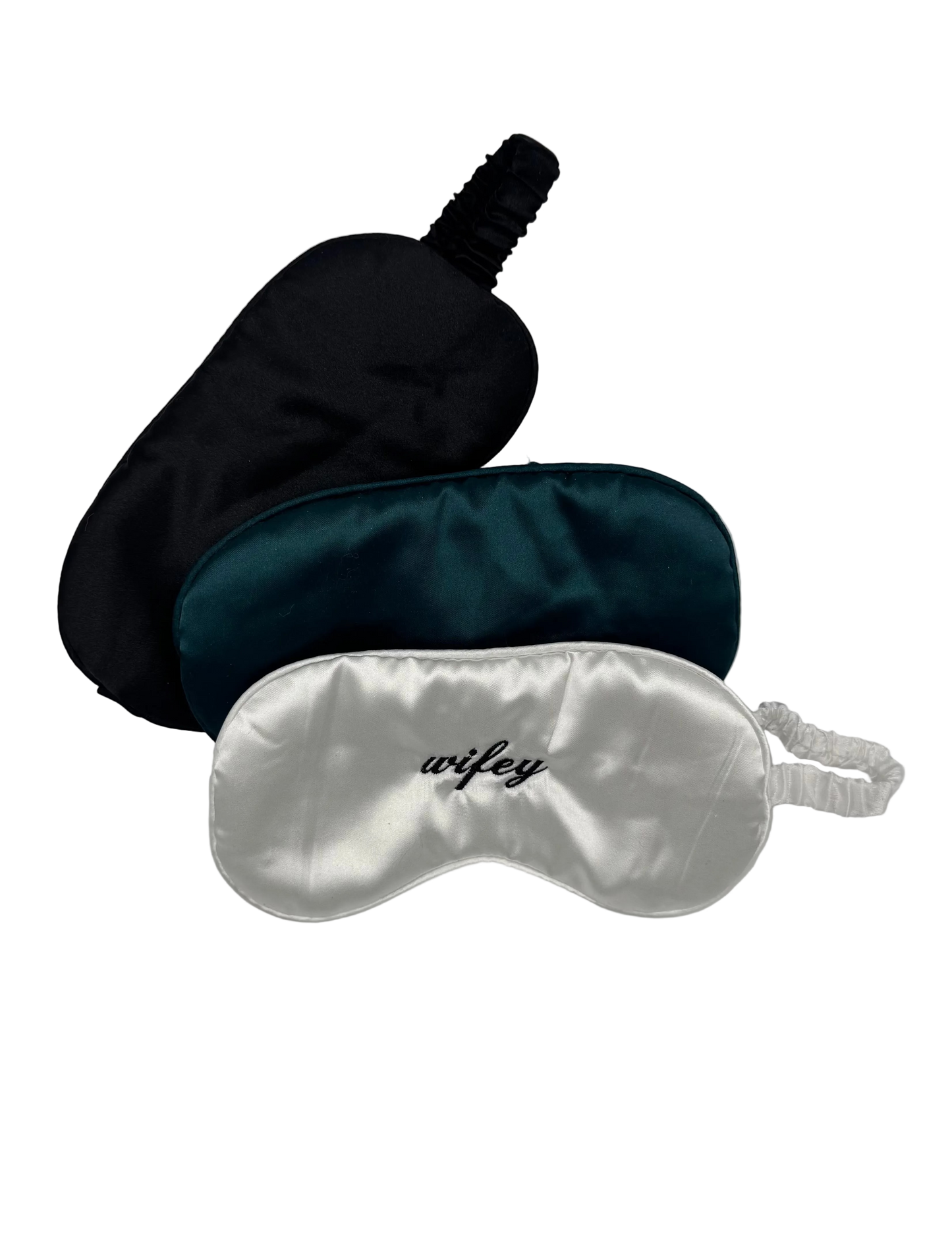 Three satin sleep masks in black, green, and silver on a light gray background.